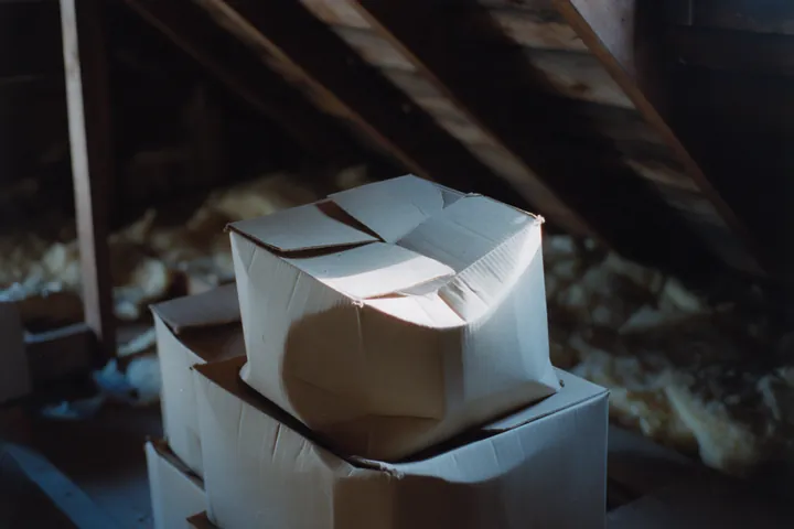 Folded cardboard boxes stacked in an unfinished attic.
